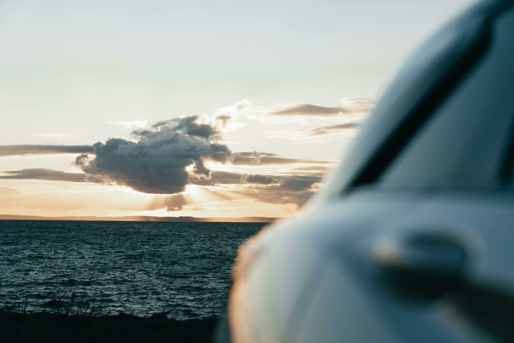 pexels photo 33980818 33980818 1 Beautiful sunset with dramatic clouds over ocean, framed by a car in the foreground.